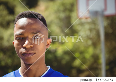 African American male standing at basketball court wearing blue jersey near hoop, copy space African American male standing at basketball court wearing blue jersey near hoop, copy space 133290873