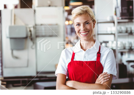 Female barista wearing red apron standing at counter using espresso machine with cups, copy space 133290886