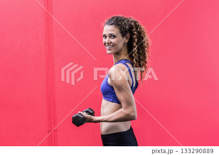 Athletic woman standing in gym wearing sportswear and holding black hex dumbbell, copy space Athletic woman standing in gym wearing sportswear and holding black hex dumbbell, copy space 133290889