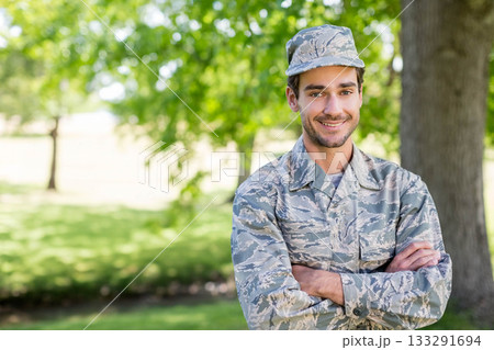 Male soldier standing outdoors on sunlit grassy lawn wearing camouflage uniform and cap, copy space Male soldier standing outdoors on sunlit grassy lawn wearing camouflage uniform and cap, copy space 133291694