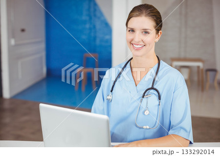 Female nurse wearing scrubs and stethoscope, sitting at desk using laptop in reception, copy space Female nurse wearing scrubs and stethoscope, sitting at desk using laptop in reception, copy space 133292014