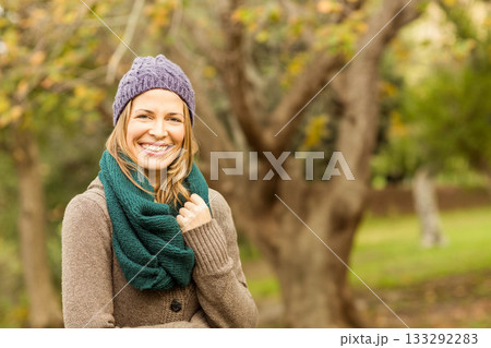 Woman standing in park in autumn wearing purple beanie green scarf and brown cardigan, copy space 133292283