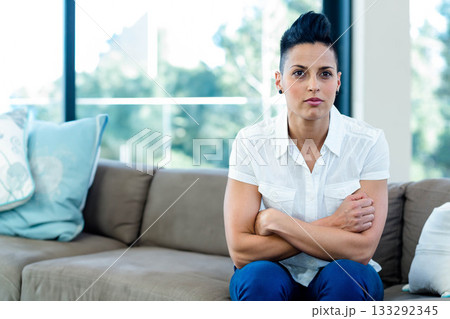Early 30s woman sitting on taupe sofa in lounge with blue cushions and windows, copy space Early 30s woman sitting on taupe sofa in lounge with blue cushions and windows, copy space 133292345