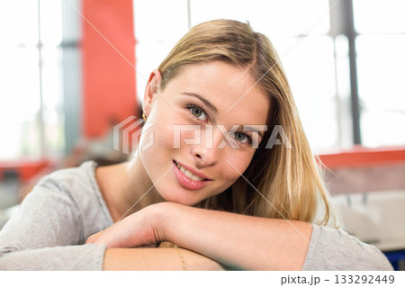 Teenage female student leaning on table in study lounge wearing gray top, hoops and bracelet 133292449