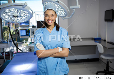 Female surgical nurse in scrubs standing in operating room at head of table under LED lights Female surgical nurse in scrubs standing in operating room at head of table under LED lights 133292483