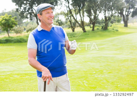 Senior African American man standing on golf course fairway wearing cap holding golf club and glove 133292497