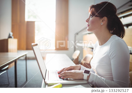 Woman student reviewing papers in lecture hall with laptop highlighter smartwatch, copy space Woman student reviewing papers in lecture hall with laptop highlighter smartwatch, copy space 133292527