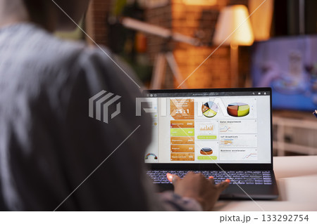 Laptop screen shows business analytics as african american woman reviews data and prepares reports at home. Focused female freelancer develops marketing strategies using digital device on desk. Laptop screen shows business analytics as african american woman reviews data and prepares reports at home. Focused female freelancer develops marketing strategies using digital device on desk. 133292754