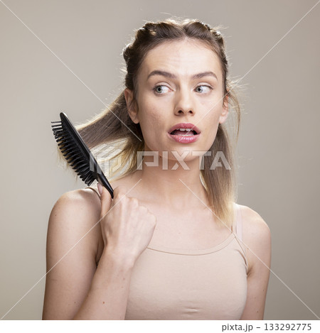 Portrait of natural graceful woman brushing her hair with a brush in studio, symbolizing pampering routine and self care for wellness and self esteem. Model using beauty accessories and tools. 133292775