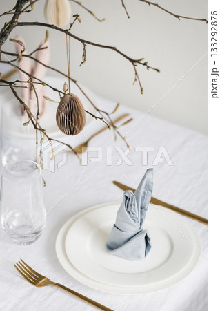 Easter table setting with bunny ear napkins and paper eggs hanging on branches. Easter table setting with bunny ear napkins and paper eggs hanging on branches. 133292876