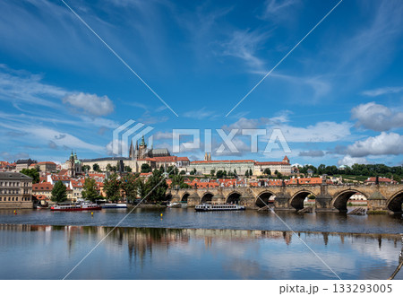Prague, Czech Republic, August 9, 2023. A shot with an enchanting view of the castle and cathedral dominating the hill, with the Vltava River flowing at its foot, traversed by tourist boats. 133293005
