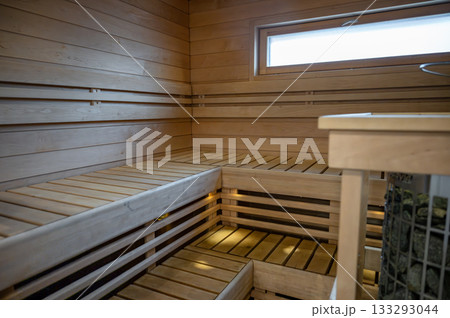 Empty modern wooden Finnish sauna interior with benches, warm lighting and clean design 133293044