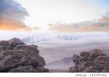 Jagged rocks in flat design are standing on summit revealing cloud inversion under pastel sky Jagged rocks in flat design are standing on summit revealing cloud inversion under pastel sky 133293208