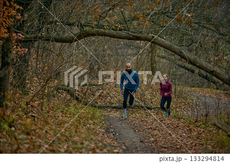 Two runners pushing uphill through dense autumn woods Two runners pushing uphill through dense autumn woods 133294814