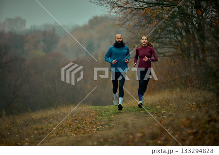 Couple trail running forward on forest path with focused stamina Couple trail running forward on forest path with focused stamina 133294828