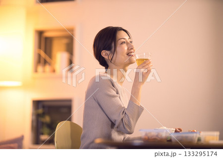 ビールを飲みながら夕食を食べるミドル女性 133295174