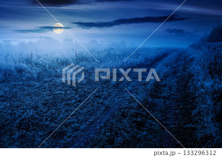 autumn landscape with dirt road through rural field in hoarfrost and fog at night. beautiful view of a countryside in mountains in full moon light. frosty weather. abandoned area needs investment autumn landscape with dirt road through rural field in hoarfrost and fog at night. beautiful view of a countryside in mountains in full moon light. frosty weather. abandoned area needs investment 133296312