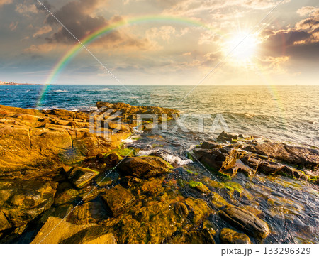 sunset at the rocky sea beach. beautiful view of coast landscape in summer. sun over horizon and cloudy sky. dramatic scenery with rock formations under rainbow. great seascape for weekend background sunset at the rocky sea beach. beautiful view of coast landscape in summer. sun over horizon and cloudy sky. dramatic scenery with rock formations under rainbow. great seascape for weekend background 133296329