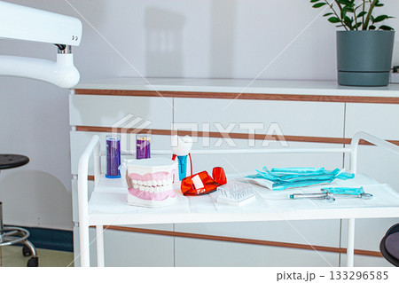 Various instruments, dental models, and hygiene items are laid out on the table in the dental office. natural light 133296585