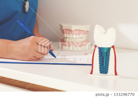 A dentist in a blue uniform studies patient information and prepares for treatment in a modern dental office A dentist in a blue uniform studies patient information and prepares for treatment in a modern dental office 133296770