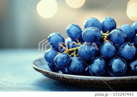 Fresh Blue Grapes with Water Droplets on Plate Under Soft Blurred Background Lighting 133297443
