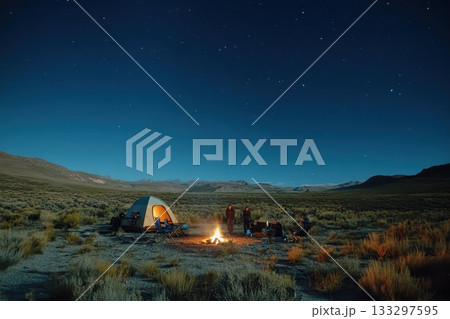 A group of people are sitting around a campfire in a desert A group of people are sitting around a campfire in a desert 133297595