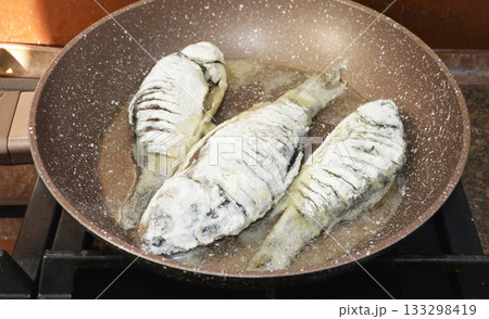 cooking freshwater fish crucian carp in a frying pan cooking freshwater fish crucian carp in a frying pan 133298419