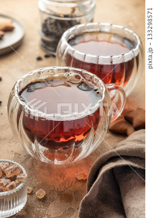 Black tea in two transparent glass cups on brown textured table background. Cozy breakfast teatime 133298571