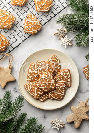 Gingerbread Christmas Cookies shaped like trees with icing decoration on a plate on white marble table background. Christmas baking, top view 133298606