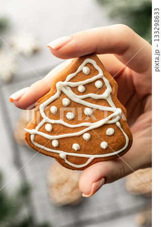 Freshly Baked gingerbread Christmas Cookie shaped like tree holded in hand close up. Christmas baking, top view Freshly Baked gingerbread Christmas Cookie shaped like tree holded in hand close up. Christmas baking, top view 133298633