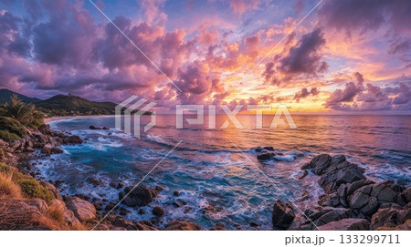 Dramatic sunset over tropical coastal landscape with rocky shoreline, turquoise waves, and vibrant pink and orange clouds reflecting on ocean water at golden hour 133299711