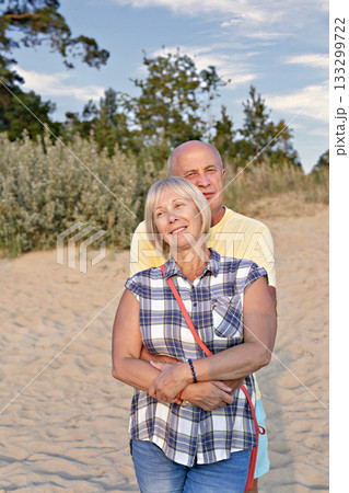 Happy senior baby boomers couple on sandy beach at golden hour Happy senior baby boomers couple on sandy beach at golden hour 133299722