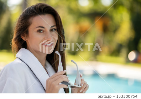 Beautiful young woman in white bath robe feeling enjoyed and confident 133300754