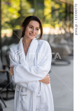 Pretty young woman in white bath robe looking relaxed and smiling 133300770