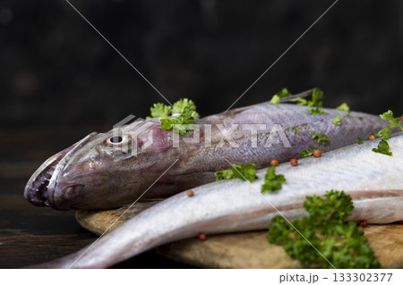 Fresh European hake fish on wooden board with parsley, Raw uncooked Merluccius merluccius close-up 133302377