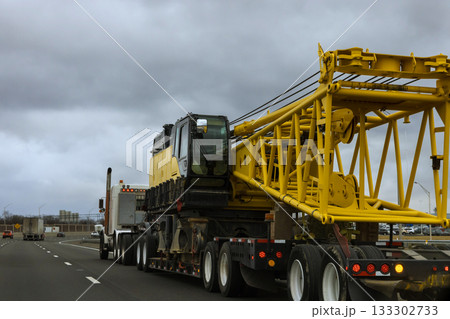 Heavy construction crane being transported on American highway in busy urban area Heavy construction crane being transported on American highway in busy urban area 133302733