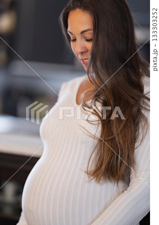 Pregnant Woman in White Attire Contemplating in Serene Home Environment 133303252