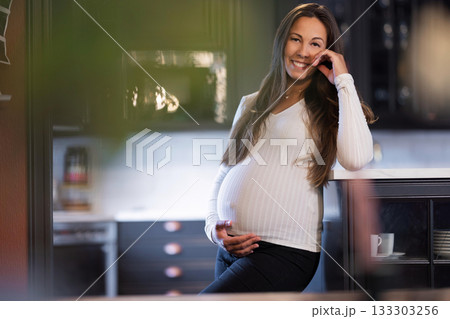 Pregnant woman smiling warmly while resting in a cozy kitchen setting 133303256
