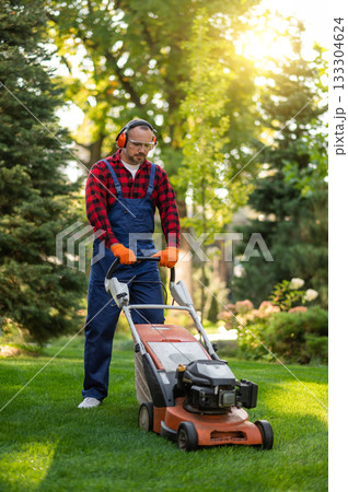 Professional landscaper in protective gear holding mower 133304624