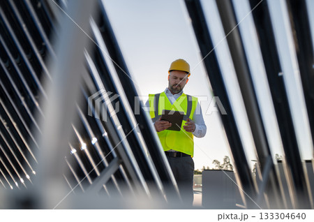 Male engineer inspecting solar panels with tablet outdoors Male engineer inspecting solar panels with tablet outdoors 133304640