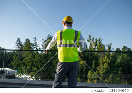 Technician in safety vest standing near solar panel field 133304649