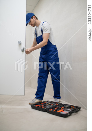 Plumber repairing toilet door handle with screwdriver in restroom Plumber repairing toilet door handle with screwdriver in restroom 133304755