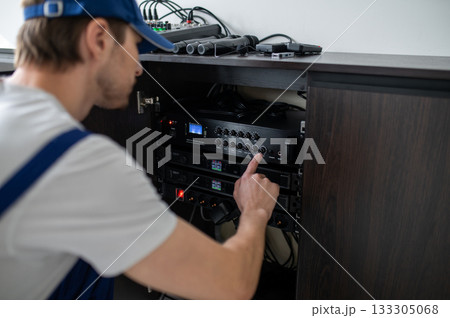 Technician adjusting stationary sound system in office Technician adjusting stationary sound system in office 133305068