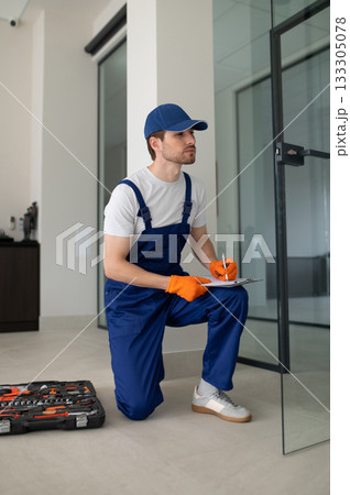 Technician installing handles and locks on glass doors 133305078