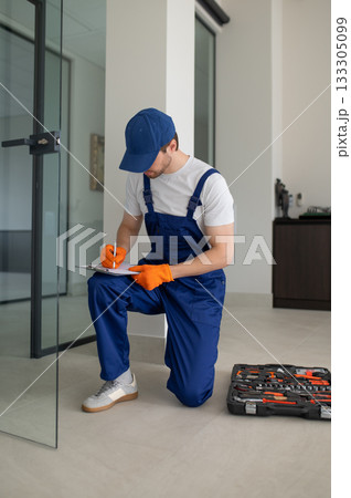Handyman working on hardware installation for office glass partition 133305099