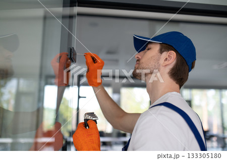 Worker fitting handles and locks on glass partition Worker fitting handles and locks on glass partition 133305180
