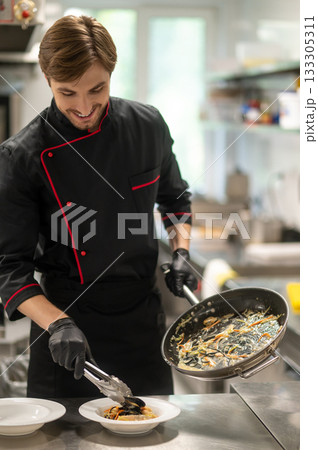 Chef cooking seafood or pasta with sauce in kitchen 133305311