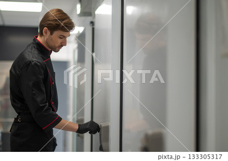 Chef in uniform moving through modern kitchen interior 133305317
