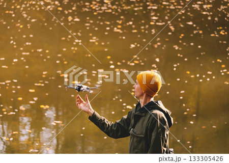 Man Flying Drone against Autumn Lake 133305426
