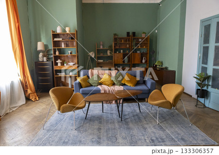 Interior of a cozy living room with green walls, a sofa, armchairs and a bookshelf Interior of a cozy living room with green walls, a sofa, armchairs and a bookshelf 133306357